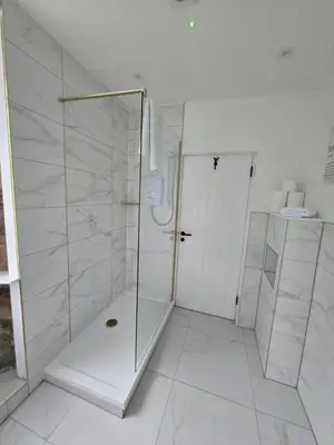 a white bathroom with a shower and a sink at Ben Lomond Apartment in Tarbet