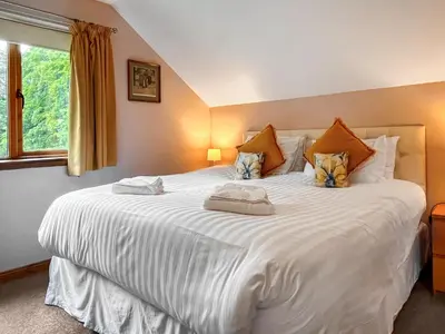 a large white bed in a room with a window at Foxglove Cottage 1 - Uk50019 in Drymen