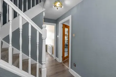 a hallway with blue walls and a staircase with white railings at Free Parking - Central - Sleeps 8 - 3 Bedrooms in Livingston