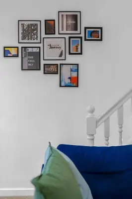 a staircase with a blue couch and pictures on the wall at Free Parking - Central - Sleeps 6 - 2 Bedrooms in East Calder