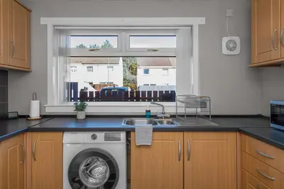 a kitchen with a washing machine and a window at Free Parking - Central - Sleeps 6 - 2 Bedrooms in Livingston