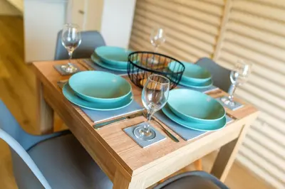 a wooden table with plates and wine glasses on it at Cultybraggan Hut 38 - Accessible in Comrie