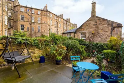 a patio with a table and chairs and a building at New Town Cottage in Edinburgh