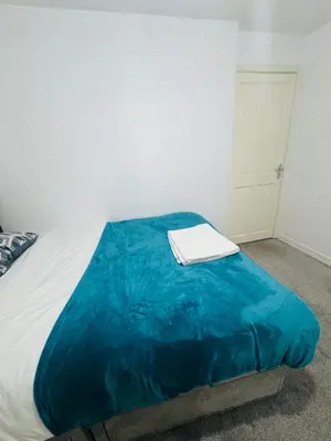 a bed with a blue blanket and a book on it at Private Room in Glasgow City in Hillfoot