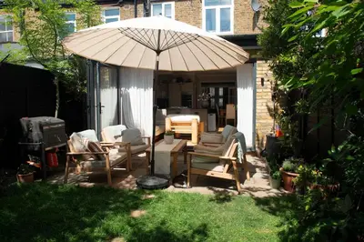 a patio with chairs and an umbrella in a yard at Wimbledon Tennis House in Moffat