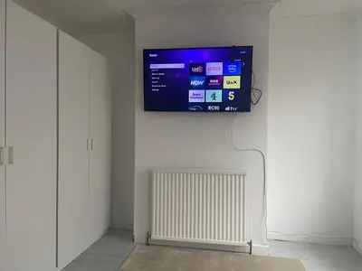 a flat screen tv hanging on a wall with a radiator at Home in Reading Uni Area in Moffat