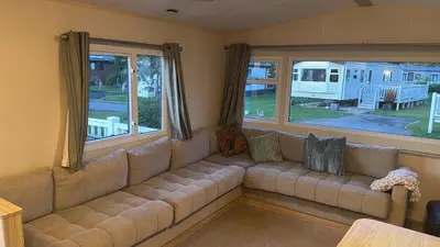 a couch in a living room with windows and a rv at Tattershall caravan with private hot tub in Moffat