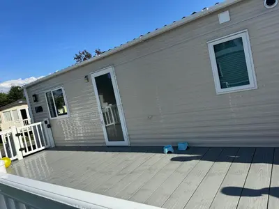 a house with a wooden deck next to a building at Tattershall caravan with private hot tub in Moffat