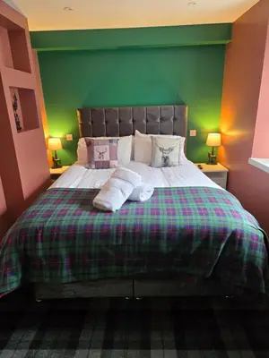 a bedroom with a large bed with a green wall at Stlll Brae Apartment in Tarbet