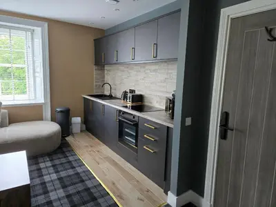 a kitchen with black cabinets and a couch in a room at Stlll Brae Apartment in Tarbet