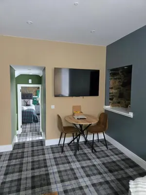 a room with a table and chairs and a tv at Stlll Brae Apartment in Tarbet