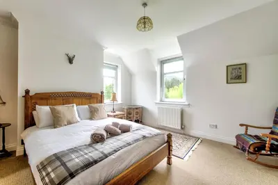 a bedroom with a large bed and a chair at Argyll Farmhouse-Idyllic Setting-Sleeps10 in Dunoon