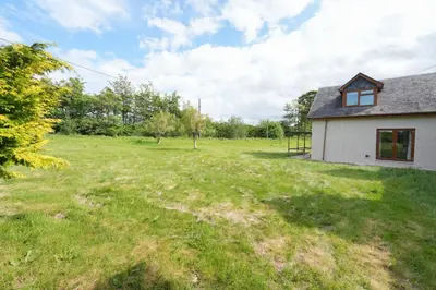 a house with a grass field next to a building at Shawsmill, outside Hurlford in Hurlford