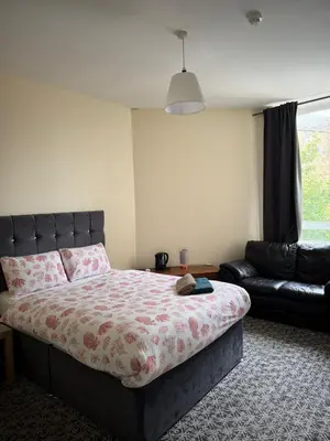 a bedroom with a bed and a leather couch at Whitefield Guesthouse in Glasgow