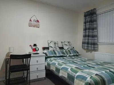 a bedroom with a bed and a chair and a desk at Studio Twenty One in Whitburn