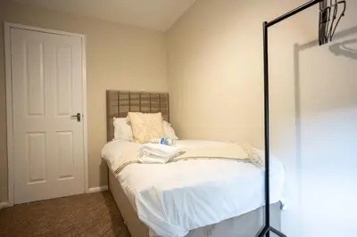 a small bedroom with a bed with white sheets at Graham House in Livingston