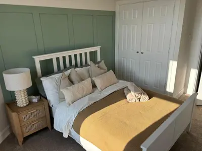a bedroom with a large bed with pillows on it at 2 bedroom first floor flat- Bonnie Stays in Troon