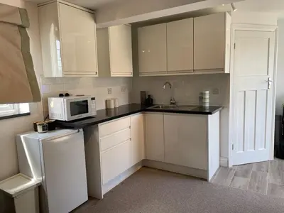 a kitchen with white cabinets and a microwave at Detached Annexe in Moffat