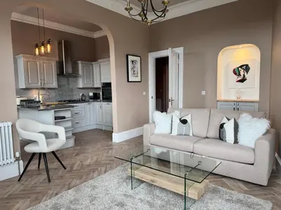 a living room with a couch and a glass table at Largs Sandringham Apartment in Largs
