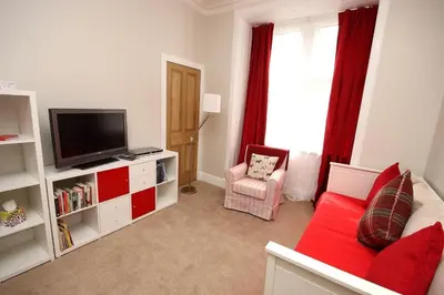 a living room with a red couch and a television at Hamish's Hame Edinburgh Licence No EH 69774 R Energy Rating C in Edinburgh