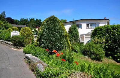 a garden with flowers and bushes next to a house at Stables Guest House in Newton Stewart