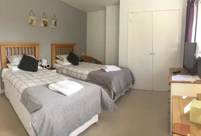 two beds in a hotel room with a television and a room at Stables Guest House in Newton Stewart