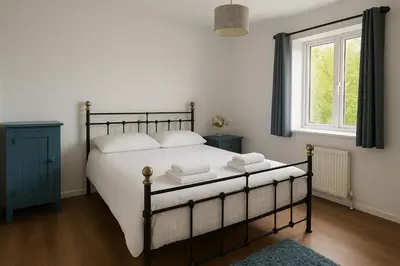 a bedroom with a bed with white sheets and a window at Cozy 2BR Flat Near City Centre Free Parking Fast Wifi in Edinburgh