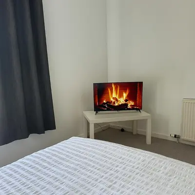 a bedroom with a tv on a table with a fireplace at Cozy 2BR Flat Near City Centre Free Parking Fast Wifi in Edinburgh