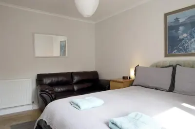 a bedroom with a bed and a leather chair at Edinburgh Family-Friendly Flat Walkable from Princess street in Edinburgh