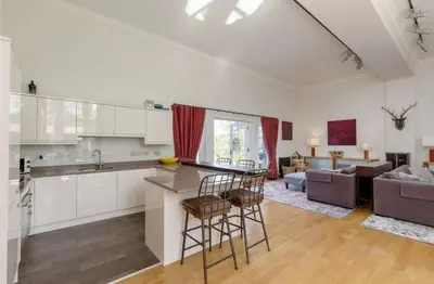 a kitchen and living room with a counter and chairs at Stunning Flat in Loch Lomond in Luss
