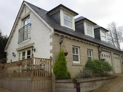 a house with a wooden fence in front of it at Bruach Lodge in Balloch