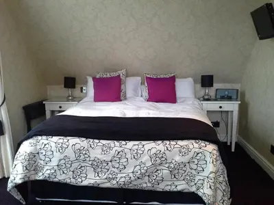a bedroom with a large bed with pink pillows at Bruach Lodge in Balloch