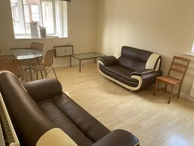 a living room with a leather couch and a table at 2 bed flat - TW7 4NH in Moffat