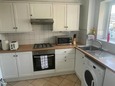 a kitchen with white cabinets and a stove and a microwave at 2 bed flat - TW7 4NH in Moffat