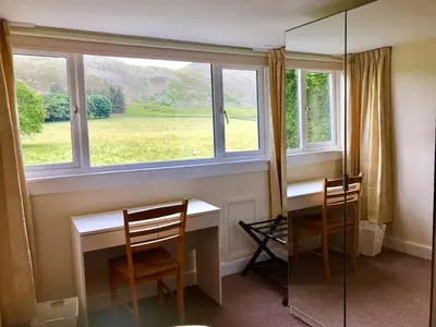 a room with a desk and two chairs and a window at Wood Cottage in Peebles