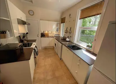 a large kitchen with white cabinets and a window at Wood Cottage in Peebles