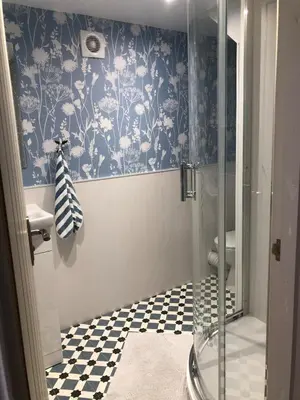 a bathroom with a shower with blue and white wallpaper at Filey in Moffat