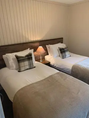 a room with two beds and a lamp on a table at Breacan Lodge in Hunters Quay
