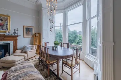 a dining room with a table and a large window at Luxury West End flat with stunning bay window views in Edinburgh