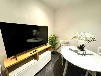 a living room with a flat screen tv and a table at Private 1 bed flat Knightsbridge, Chelsea in Moffat