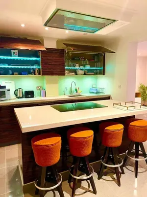 a kitchen with a counter with orange bar stools at Private 1 bed flat Knightsbridge, Chelsea in Moffat