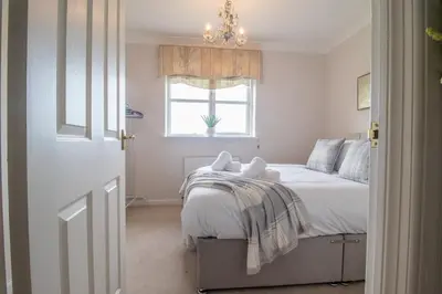 a bedroom with a bed with a chandelier and a window at The Well - 3 bedroom apartment in Motherwell
