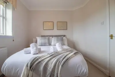 a white bedroom with a large bed with white pillows at The Well - 3 bedroom apartment in Motherwell