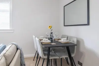 a dining room table with chairs and a table with wine glasses at Leven Loft - 2 Bed Flat in Coatbridge in Coatbridge