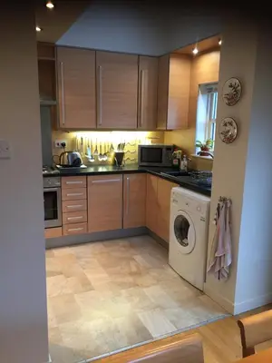 a kitchen with wooden cabinets and a washer and dryer at Morvern Cottage in Craobh Haven