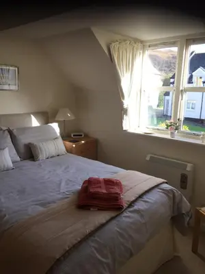 a bedroom with a large bed with a window at Morvern Cottage in Craobh Haven