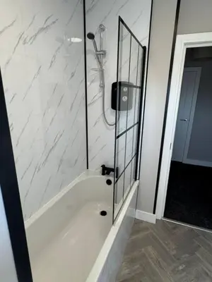 a bathroom with a shower and a tub with a mirror at 3 bedroom Falkirk flat in Falkirk