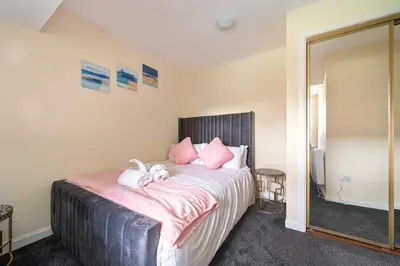 a bedroom with a bed with pink pillows and a mirror at Glasgow Apartment near Hydro & SECC, Finnieston in Glasgow