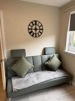 a couch in a living room with a clock on the wall at Newly Renovated Flat Edinburgh - 2 x Double Beds in Edinburgh