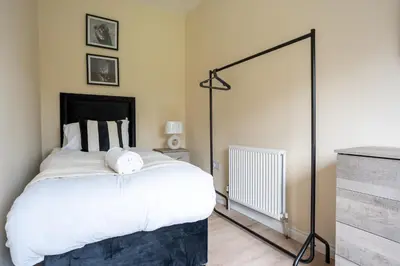 a bedroom with a large bed with white sheets at Curtis Apartment in Glasgow